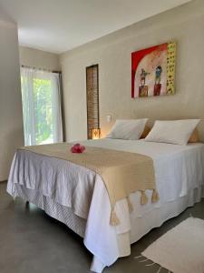 una camera da letto con un grande letto bianco con un fiore sopra di Morada das Marés a Arraial d'Ajuda