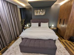 1 dormitorio con 1 cama grande y 1 reposapiés grande en Gold Crest Mall One bedroom Penthouse Apartment DHA Lahore, en Lahore