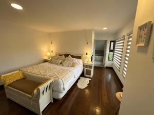 a bedroom with a large bed and a bench in it at Acogedora casa con tinaja y jacuzzi y RENT A CAR in Puerto Varas