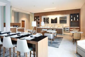 una sala da pranzo con tavoli e sedie e una cucina di AC Hotel by Marriott Raleigh North Hills a Raleigh
