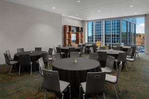 a conference room with tables and chairs and a large window at AC Hotel by Marriott Raleigh North Hills in Raleigh