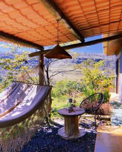 een veranda met een hangmat, een tafel en een stoel bij Vila Chappada in Alto Paraíso de Goiás