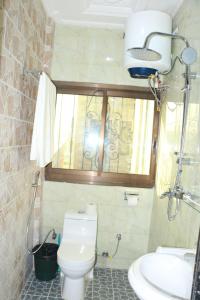 a bathroom with a toilet and a sink and a window at DEUDJUI HOTEL in Bafang