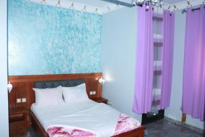 1 dormitorio con 1 cama con cortinas moradas en DEUDJUI HOTEL, en Bafang