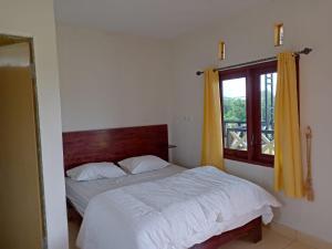 1 dormitorio con cama blanca y ventana en Berastagi Mountain View Homestay & Pizzeria en Berastagi