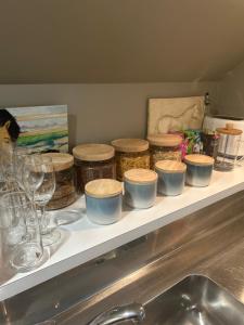 a shelf with jars and wine glasses and a sink at Summerfields B & B in Cambridge