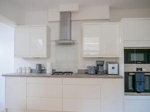 cocina con armarios blancos y encimera en Charming Oasis with Garden en Londres