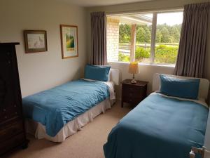 two beds in a room with a window at TayFord Cottage in Waipu