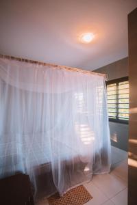 1 dormitorio con cortina blanca y ventana en La Serena Hostel, en Pipa