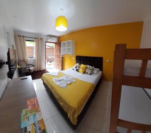 een slaapkamer met een bed met een gele muur bij Pousada Anjos - à 2 quadras do mar in Matinhos