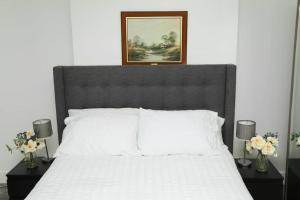 a bedroom with a white bed with a picture on the wall at Impeccable 3 bedroom house in Plumstead