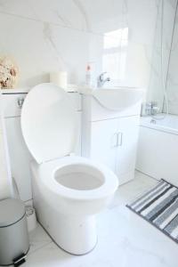 biała łazienka z toaletą i umywalką w obiekcie Impeccable 3 bedroom house w mieście Plumstead