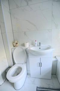 a white bathroom with a toilet and a sink at Impeccable 3 bedroom house in Plumstead