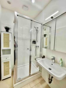 uma casa de banho branca com um chuveiro e um lavatório. em NEW!l! Exclusive Near Opera em Viena