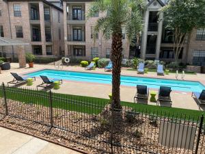 einem Pool mit Stühlen und einer Palme vor einem Gebäude in der Unterkunft Houston's City Center Apartment in Houston