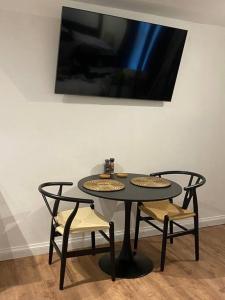 a black table with two chairs and a tv on a wall at Ultra Modern Studio Apartment, in Central Exeter in Exeter