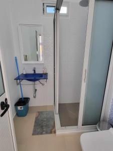 a bathroom with a shower and a blue sink at Apartamentos vista ao mar in Praia Baixo
