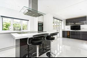a kitchen with black and white counter tops and stools at Luma Country House Hot Tube & Swim Spa E2M Stays in Effingham
