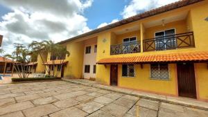 un edificio amarillo con balcón y palmeras en Condominio Sol Poente, en Salinópolis