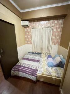 ein kleines Bett mit Kissen darauf in einem Zimmer in der Unterkunft The Suites Metro by KS Property in Bandung