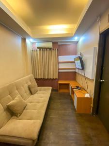ein Wohnzimmer mit einem Sofa und einem TV in der Unterkunft The Suites Metro by KS Property in Bandung