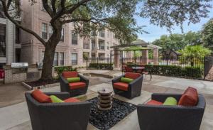 eine Terrasse mit Stühlen und Tischen sowie einem Tisch und einem Gebäude in der Unterkunft Houston's City Center Apartment in Houston