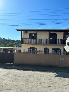 a house with a balcony and a fence at Casas Verão Bombinhas in Bombinhas