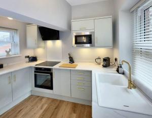 a white kitchen with white cabinets and a sink at Harrogate House Apt 3 - 2 Bed Duplex in Harrogate