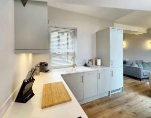 a kitchen with white cabinets and a sink and a couch at Harrogate House Apt 3 - 2 Bed Duplex in Harrogate