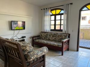 a living room with a couch and a tv at Casas Verão Bombinhas in Bombinhas