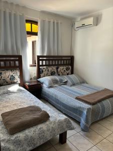 a bedroom with two beds and a window at Casas Verão Bombinhas in Bombinhas