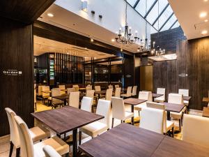 a restaurant with wooden tables and white chairs at APA Hotel Kyoto Eki Horikawadori in Kyoto