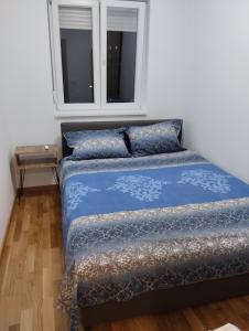 een bed met een blauw dekbed en een raam bij Paulina Apartments in Čačak