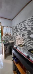 a kitchen with a stove and a stone wall at Casa Tauchin in Puerto Viejo