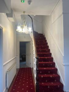 un escalier avec un tapis rouge et un lustre dans l'établissement La Vera, à South Norwood