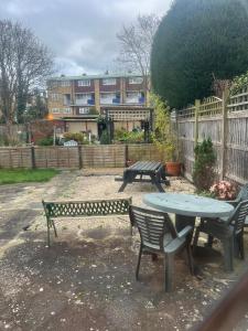 a patio with two benches and a table and a building at La Vera in South Norwood