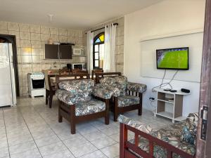a living room with a tv and a kitchen at Casas Verão Bombinhas in Bombinhas