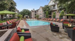 a swimming pool with chairs and tables and a swimming pool at Houston's City Center Apartment (5-Min Drive from Med Center) in Houston