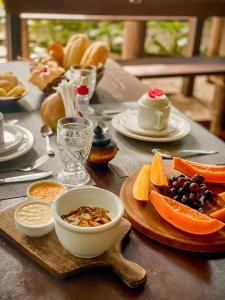 a table with plates of fruit and a bowl of food at Pousada Zen Caraiva in Caraíva