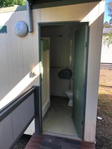 une porte ouverte menant à une salle de bains pourvue de toilettes. dans l'établissement River Bend Caravan Park, à Kanyapella