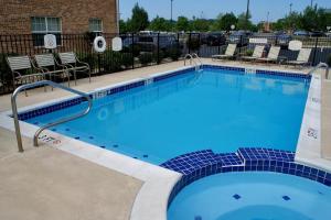 une grande piscine bleue avec des chaises dans un parking dans l'établissement TownePlace Suites Fredericksburg, à Fredericksburg