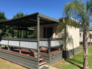 a house with a porch and a palm tree at River Bend Caravan Park in Kanyapella