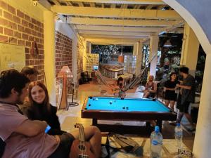 a group of people sitting around a pool table at Munay Backpacker Hostel in Montañita