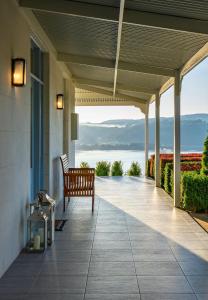 a porch with a bench and a view of the water at Villa Talia Tasmania in Wattle Grove