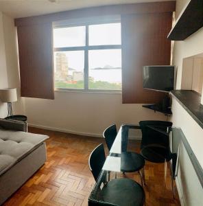sala de estar con mesa, sillas y ventana en Fronteira Leblon/Ipanema - Vista fantástica!, en Río de Janeiro