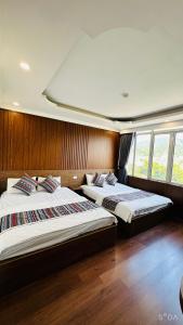 two beds in a room with wooden walls and windows at Minh Hoang Hotel & Homestay in Cao Bằng