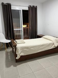 a bedroom with a bed and a chair and a window at Departamento centrico in La Cieneguita