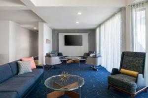 a living room with a couch and chairs and a tv at Courtyard by Marriott Phoenix Airport in Phoenix