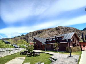 una cabaña de madera con una montaña en el fondo en Rancho Aparte Hostel en El Chaltén