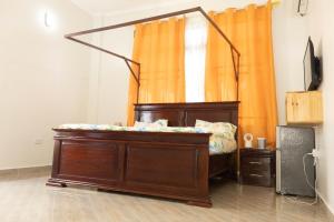 Cama en habitación con cortina naranja en Morris Multi en Dar es Salaam